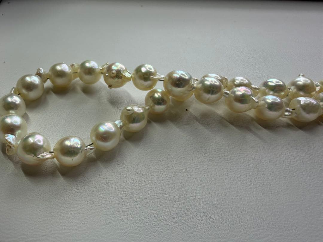 Akoya pearl necklace with 7.5mm white pearls and silver clasp laid flat on white background