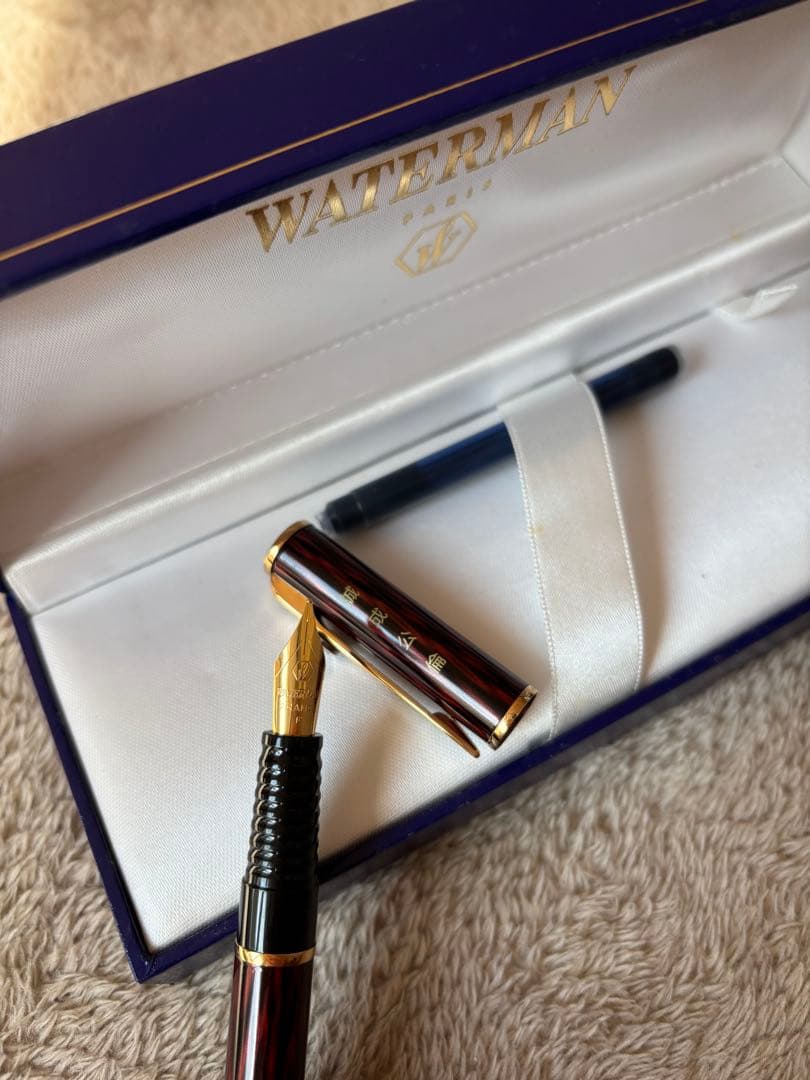 Brown WATERMAN fountain pen with logo, presented alongside a protective case and extra ink bottle
