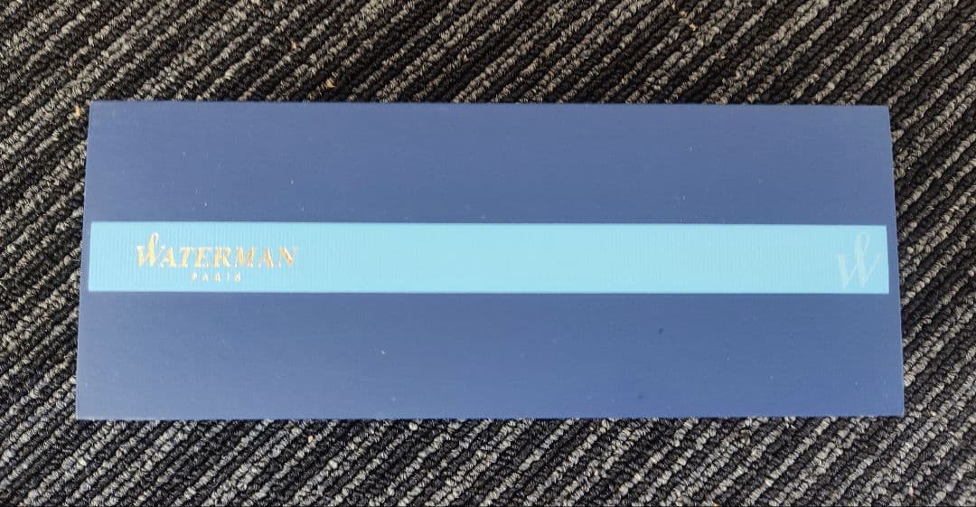 WATERMAN Paris ballpoint pen with silver wave pattern cap and black body beside a blue gift box