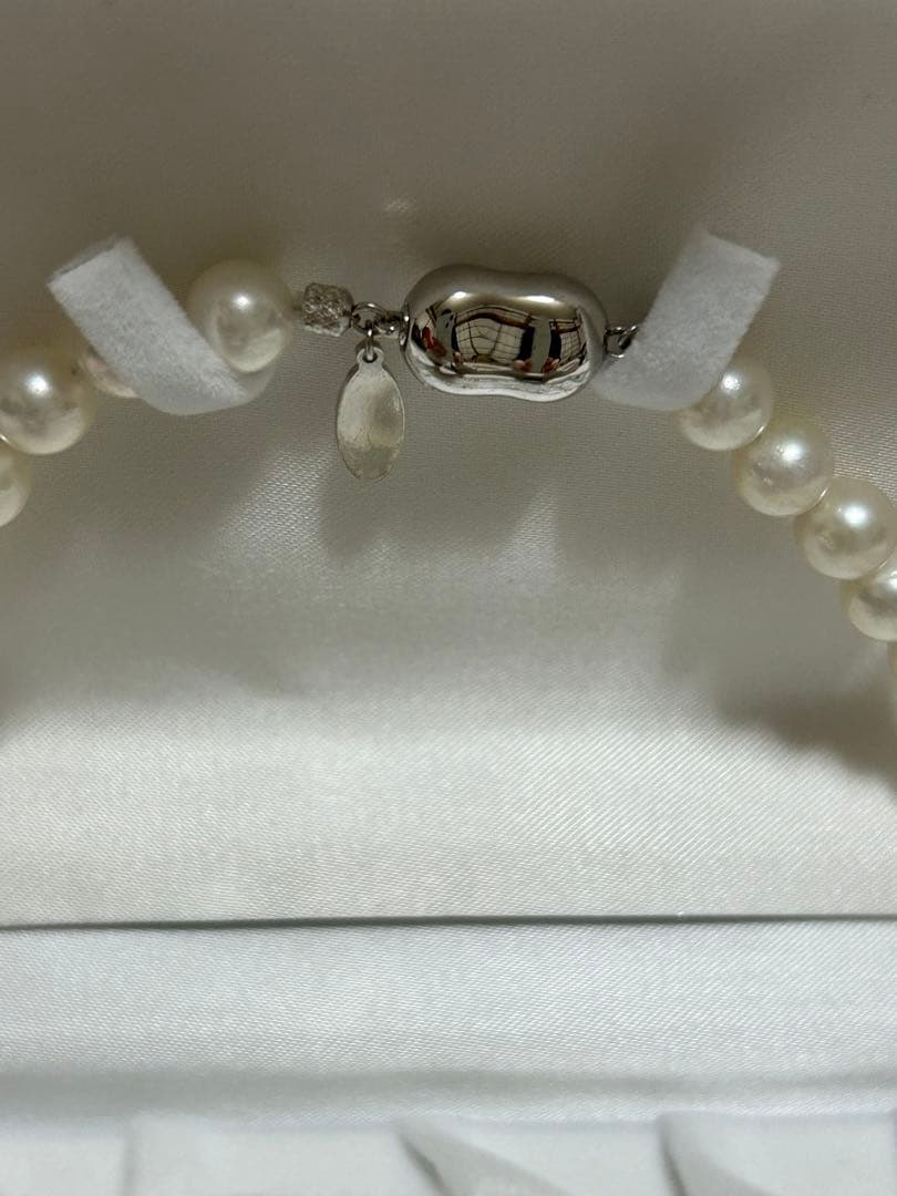 Akoya pearl choker necklace with matching pair of pearl earrings on white background