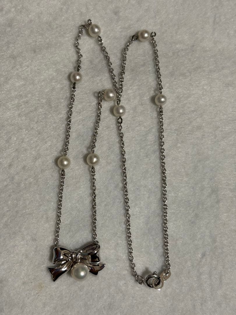 TASAKI elegant silver necklace with lustrous white pearls on a white background