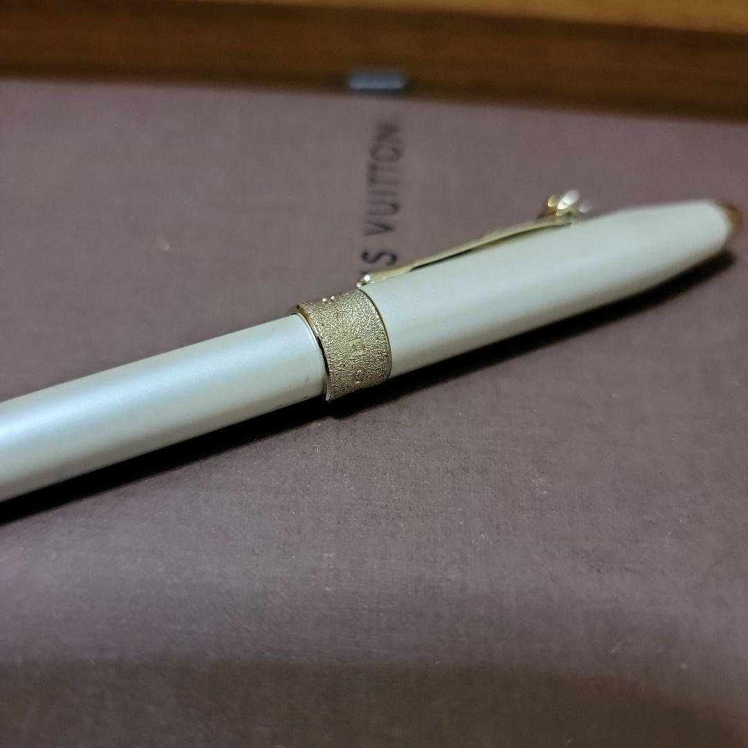 Cross ballpoint pen with white and gold metal body featuring a heart-shaped charm clip and textured center ring