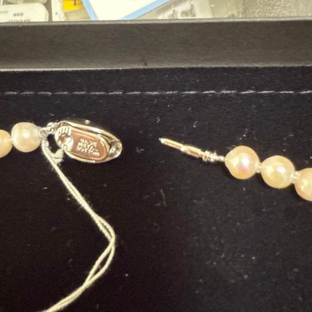 Akoya pearl necklace with 6 to 6.5mm white and pinkish pearls and silver clasp on plain background