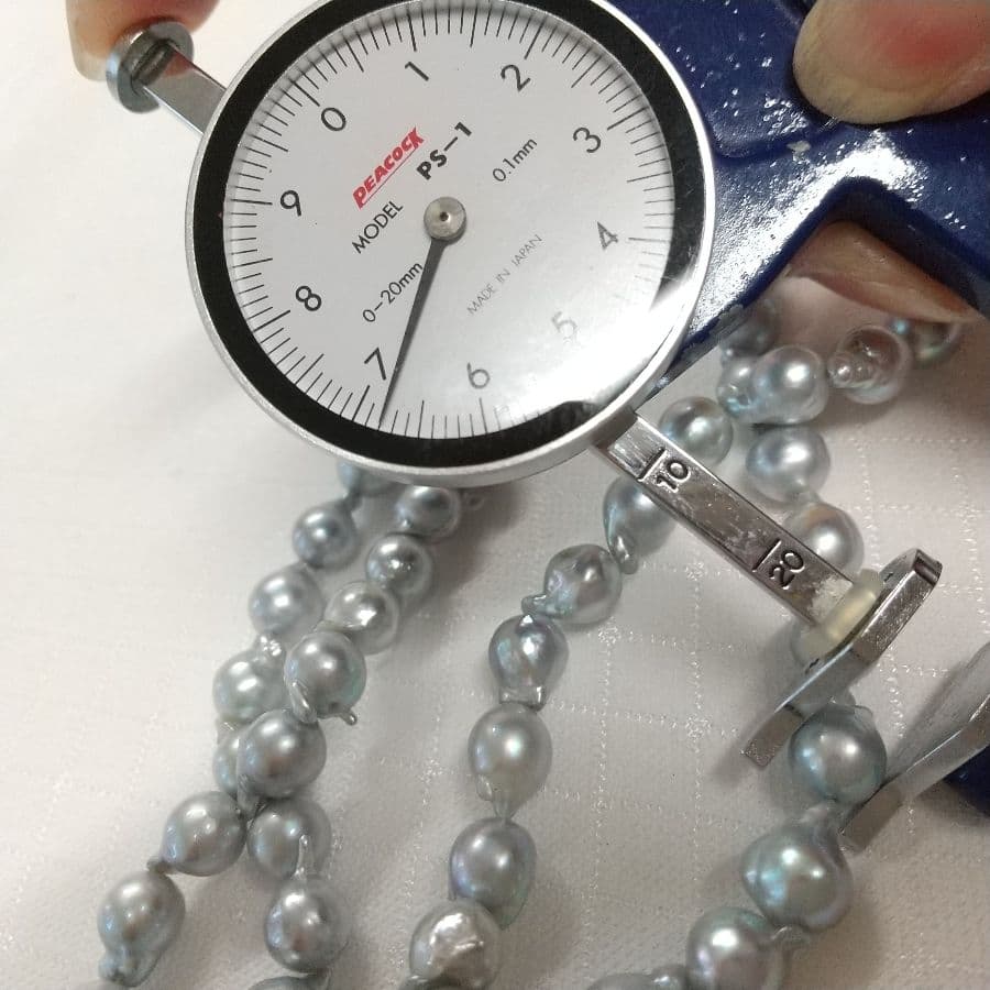 Akoya genuine pearl gray dyed baroque long necklace measuring 81.5 cm laid out on a white background