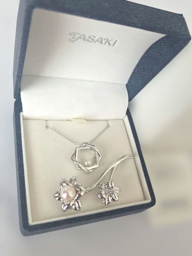 TASAKI pearl necklace with 6mm pearls and silver flower motif brooch set on white background