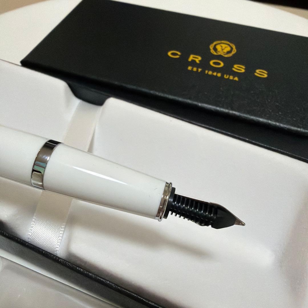 Cross white fountain pen with silver accents and two black ink cartridges on a white background