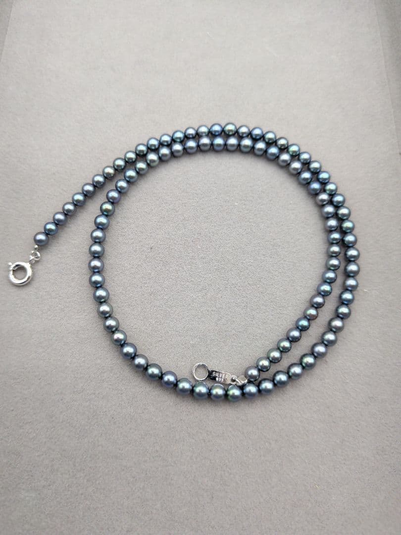 Akoya cultured pearl baby necklace with black peacock tone pearls and silver clasp on white background