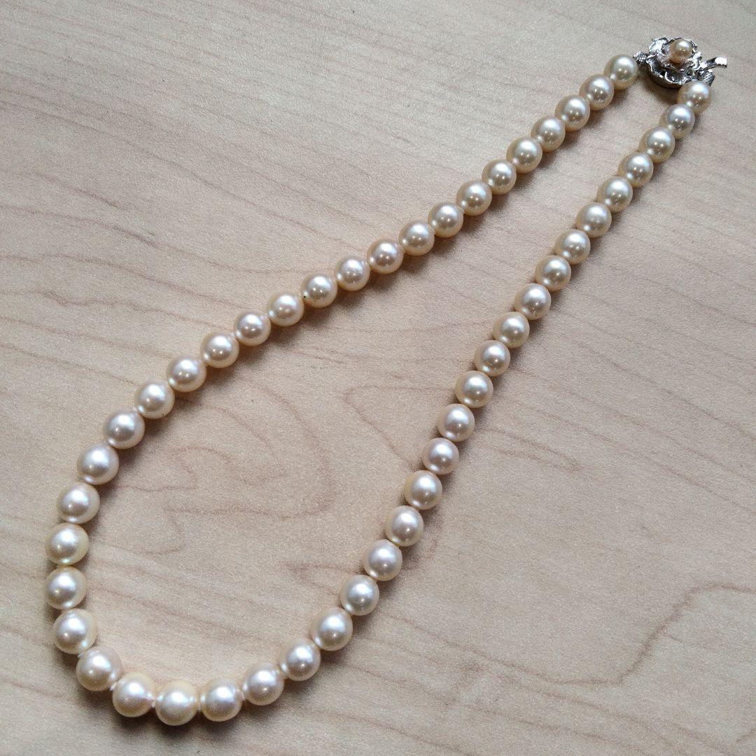 Akoya pearl necklace and matching earrings set with white pearls and silver clasp on a white background