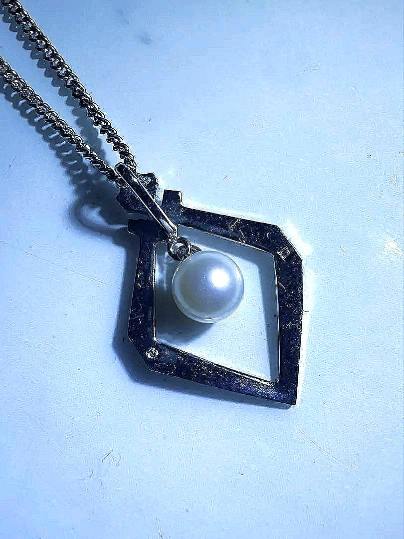 Mikimoto silver necklace with a triangle pendant swaying on a delicate chain