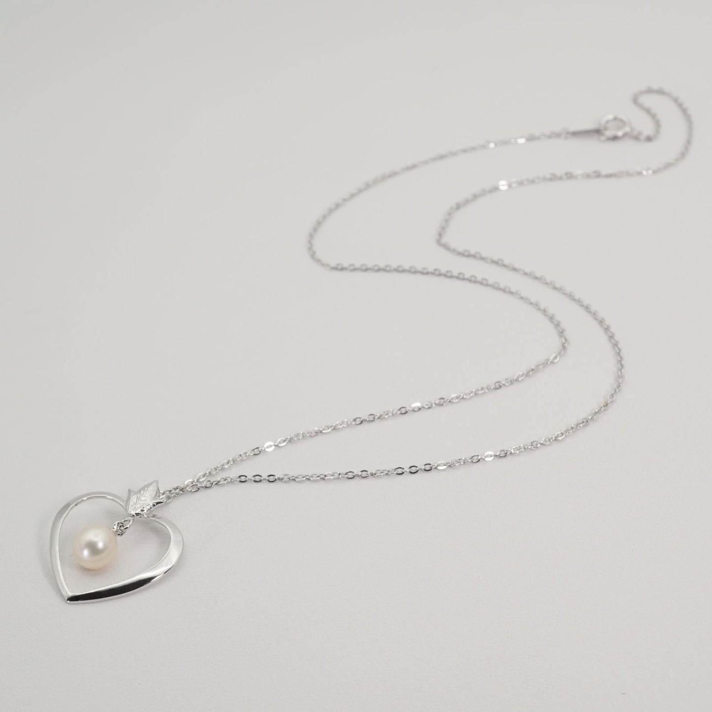 Mikimoto heart-shaped pearl necklace with silver chain displayed against white background