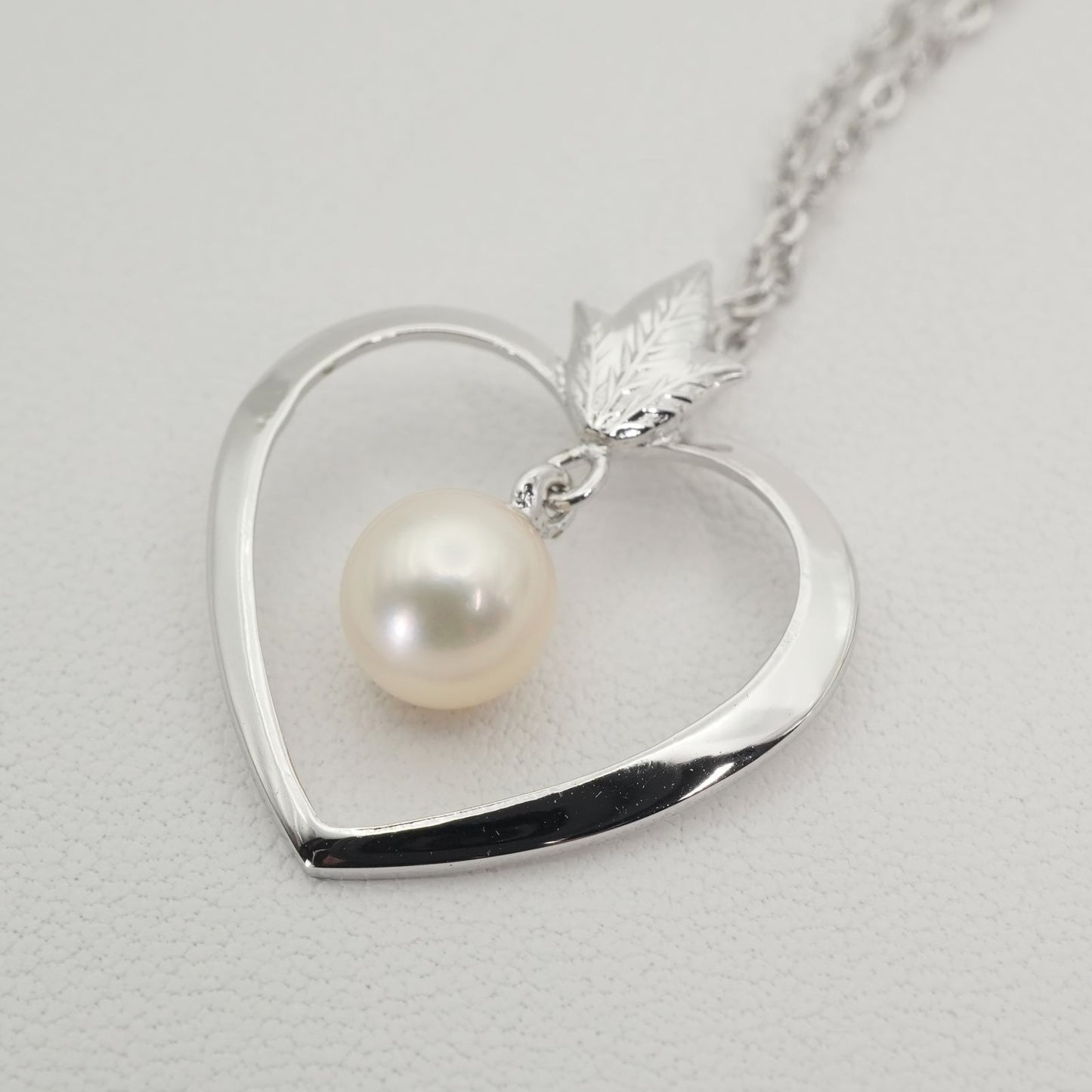 Mikimoto heart-shaped pearl necklace with silver chain displayed against white background