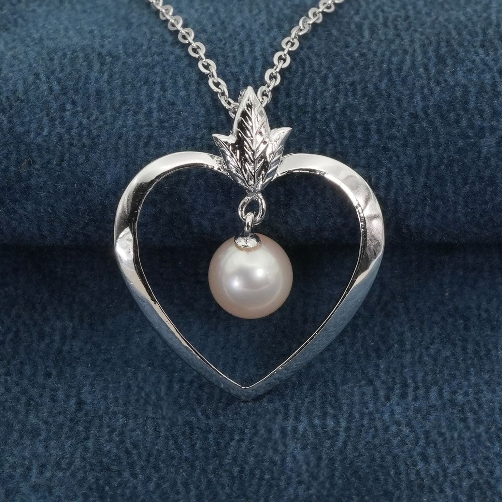 Mikimoto heart-shaped pearl necklace with silver chain displayed against white background