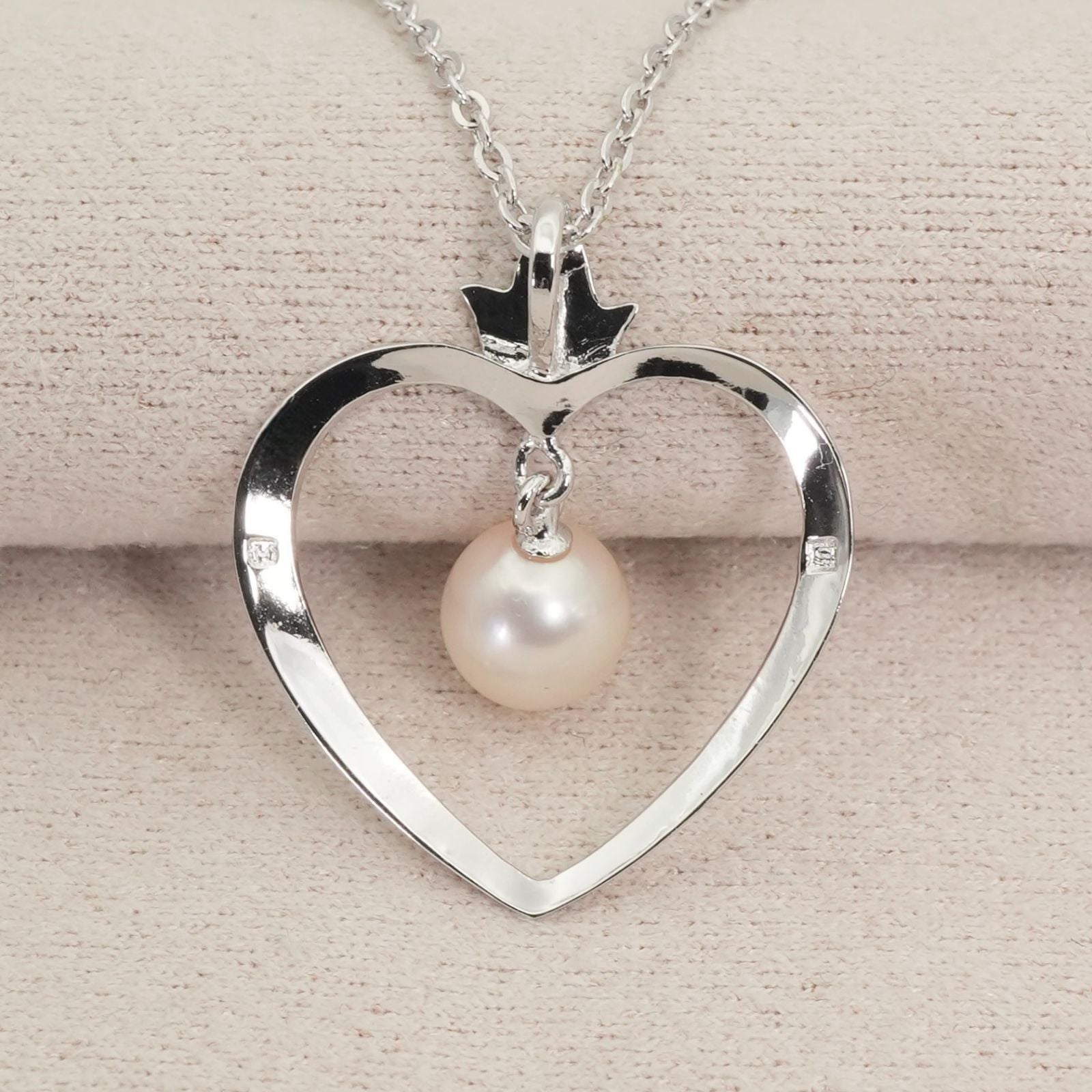 Mikimoto heart-shaped pearl necklace with silver chain displayed against white background
