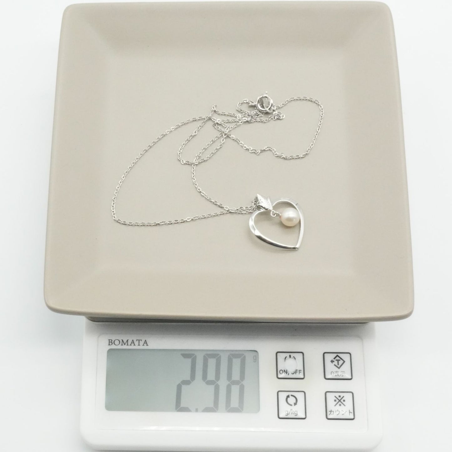 Mikimoto heart-shaped pearl necklace with silver chain displayed against white background