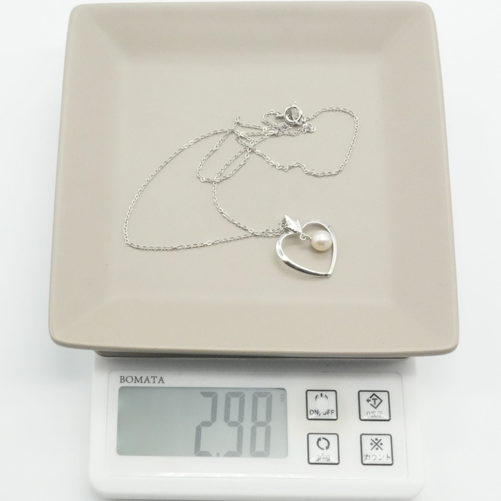 Mikimoto heart-shaped pearl necklace with silver chain displayed against white background
