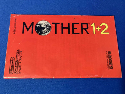 MOTHER1+2 game cartridge with damaged box and manual showing visible scratches and wear
