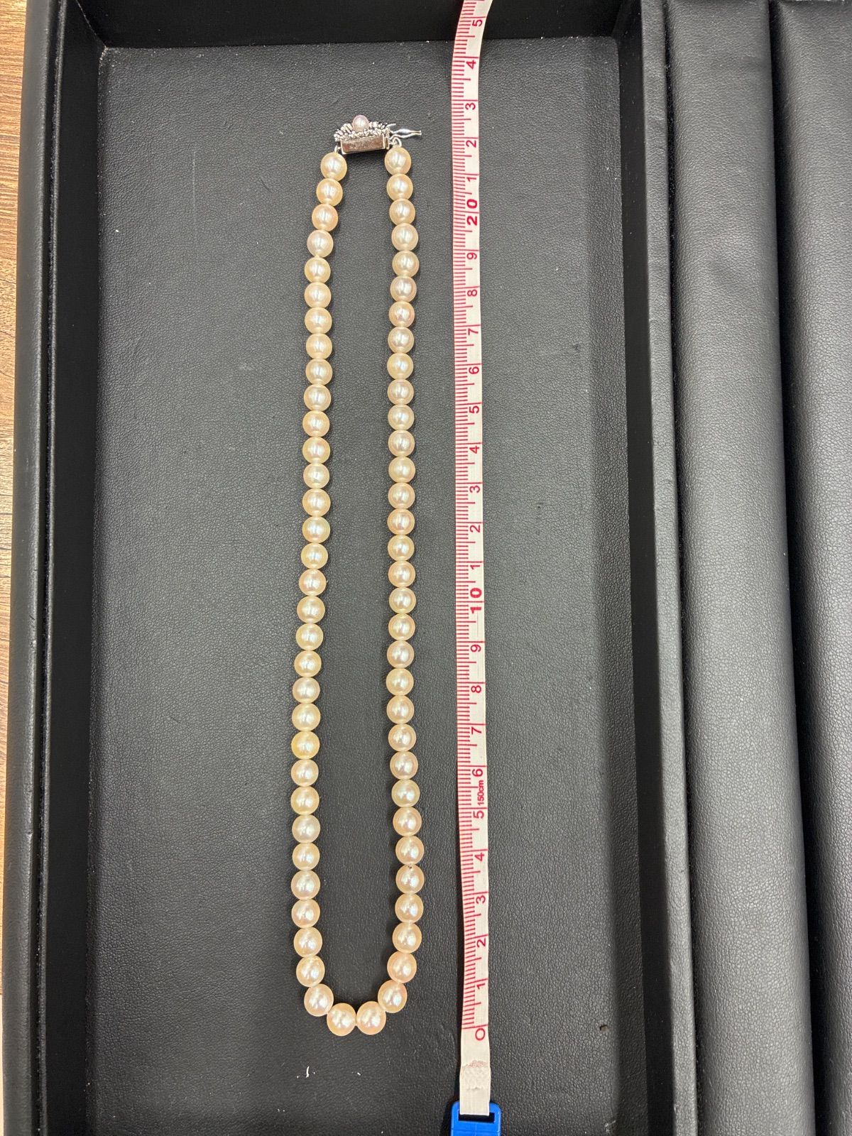 Used TASAKI pearl necklace with imprint displayed alongside its case