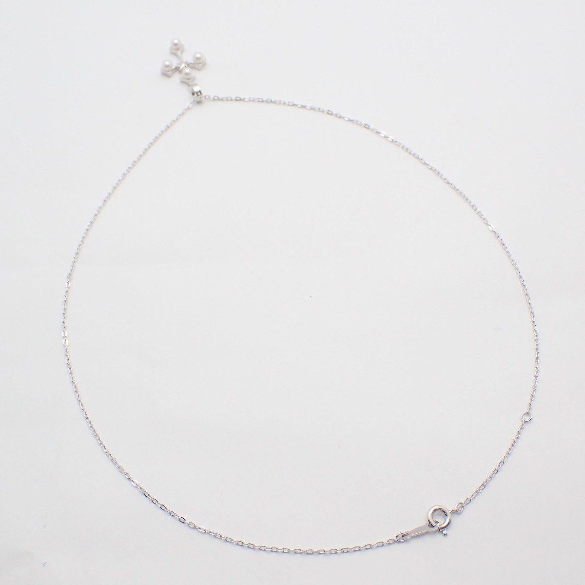 Mikimoto silver cross necklace featuring four small pearls and adjustable chain
