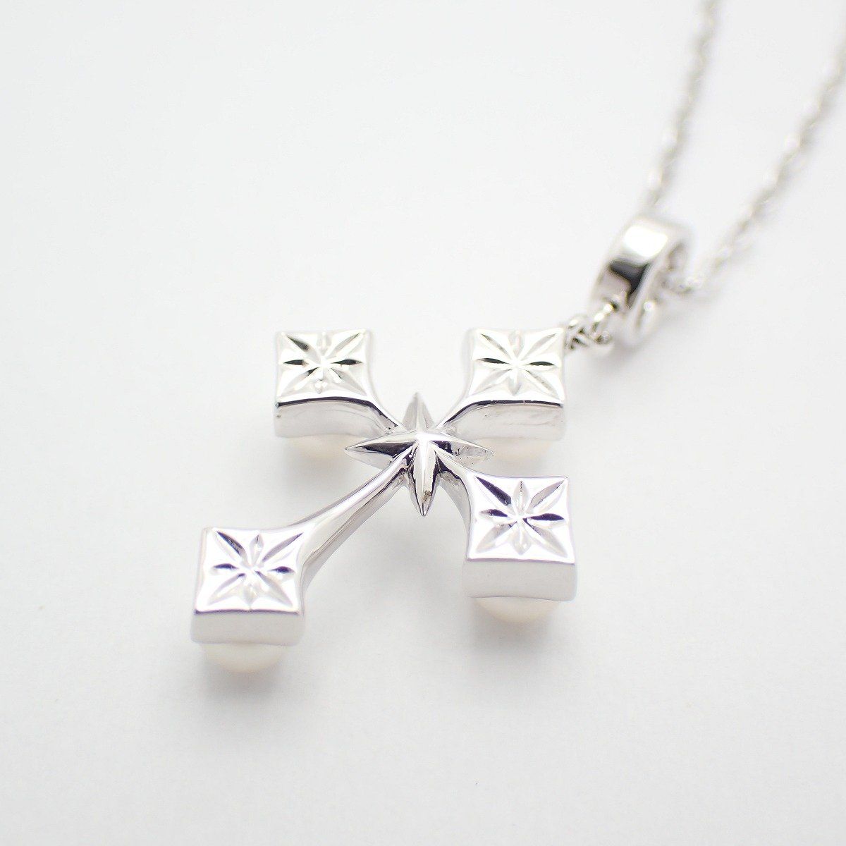 Mikimoto silver cross necklace featuring four small pearls and adjustable chain