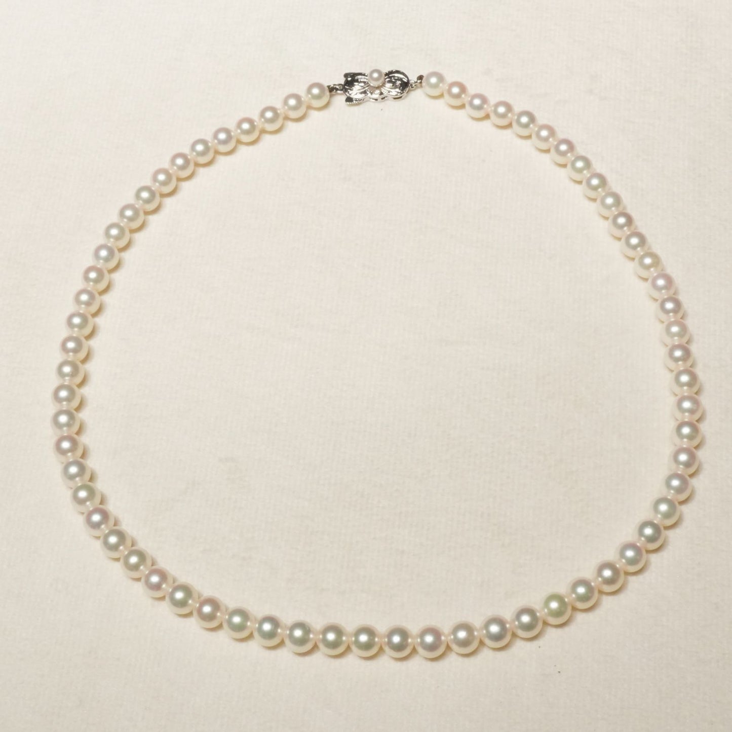 Mikimoto Akoya pearl necklace with 6.4mm pearls and silver current clasp on white background