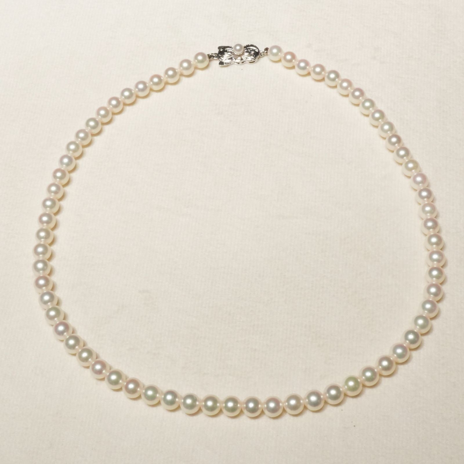 Mikimoto Akoya pearl necklace with 6.4mm pearls and silver current clasp on white background