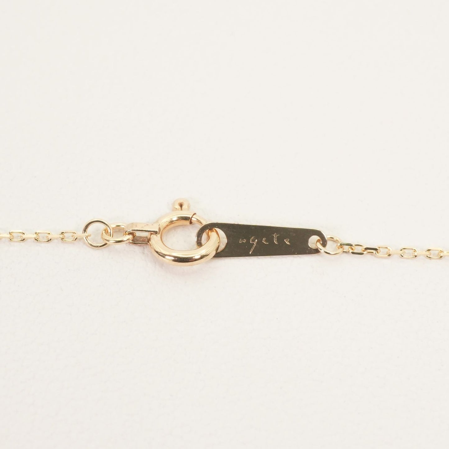 Agete K10 gold necklace chain laid out showing its fine links and polished finish