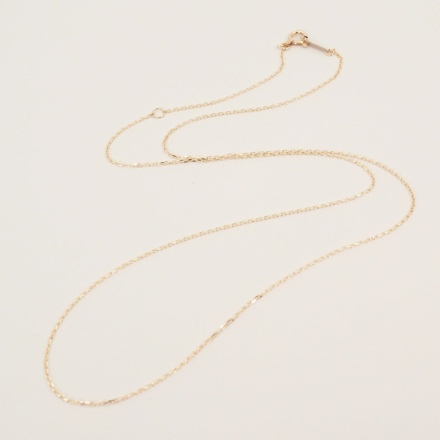 Agete K10 gold necklace chain laid out showing its fine links and polished finish