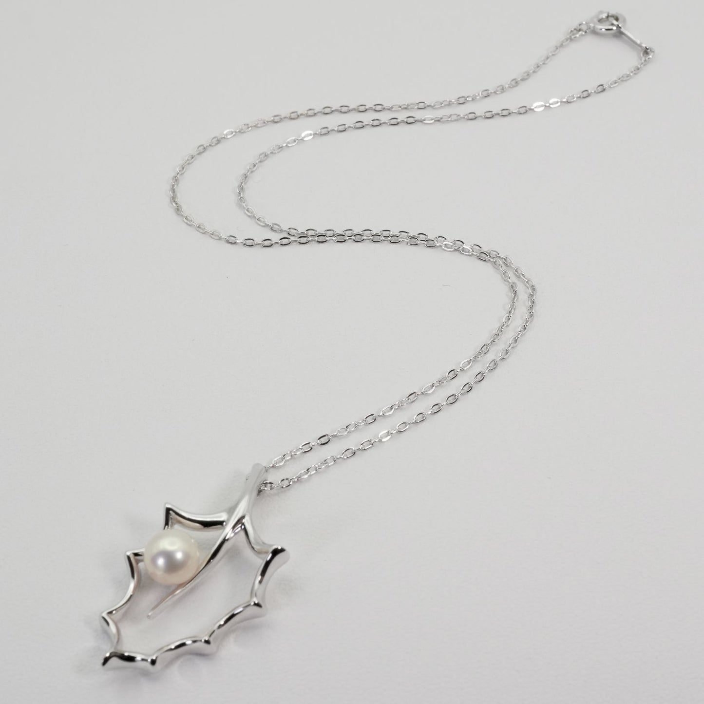 Mikimoto Hollyhock necklace featuring a silver chain and a single pearl pendant with floral design