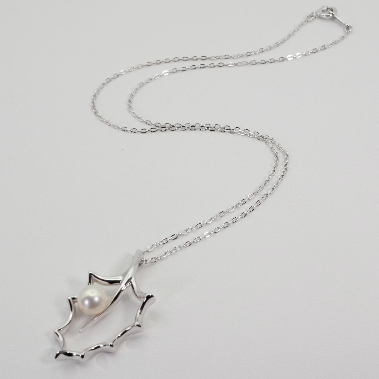 Mikimoto Hollyhock necklace featuring a silver chain and a single pearl pendant with floral design