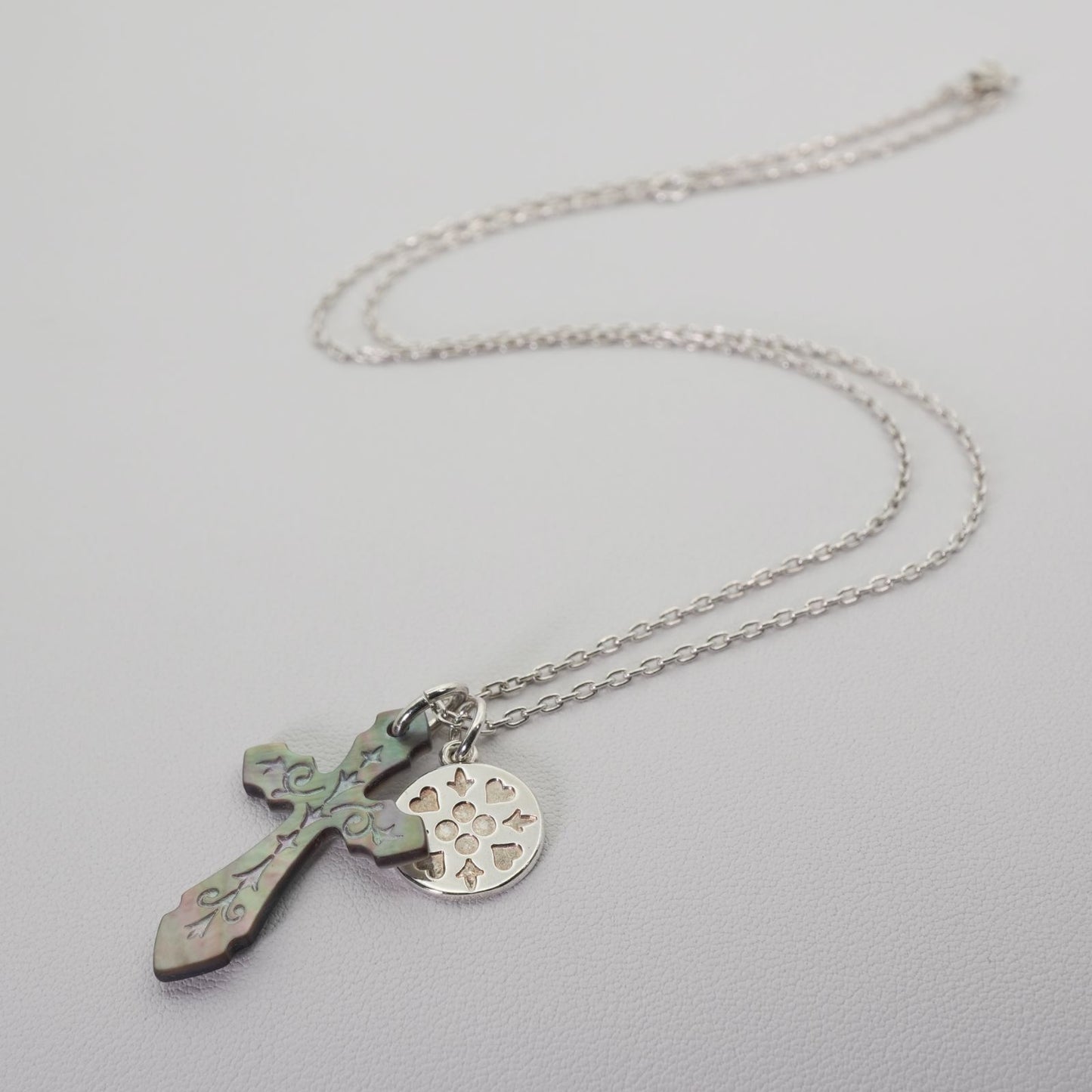 Agete silver necklace with a round shell cross charm on a delicate chain