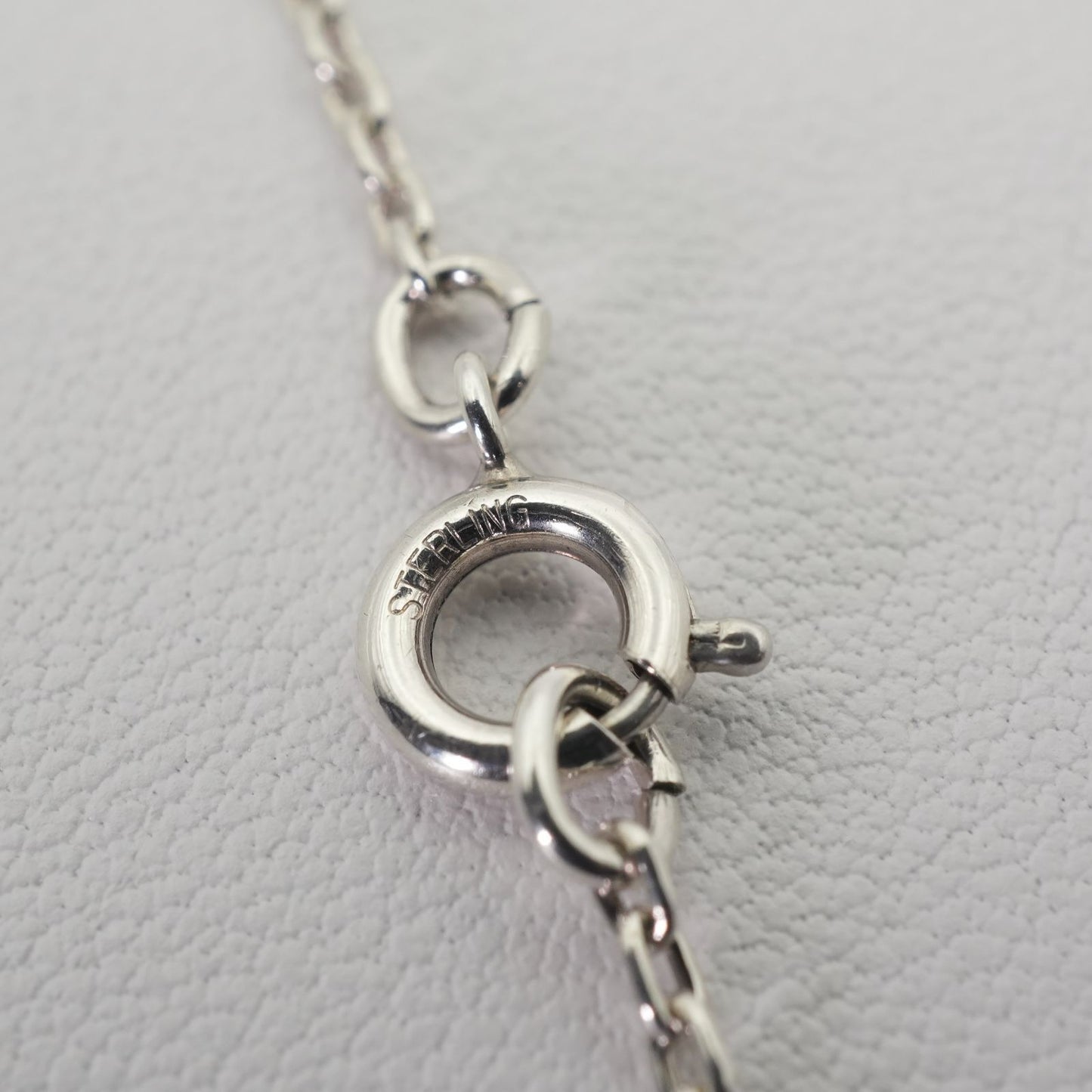 Agete silver necklace with a round shell cross charm on a delicate chain