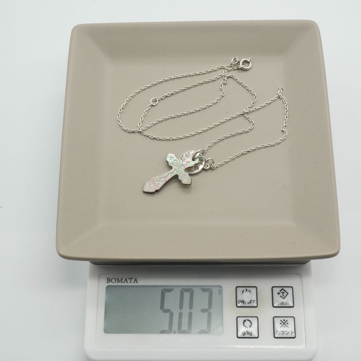 Agete silver necklace with a round shell cross charm on a delicate chain