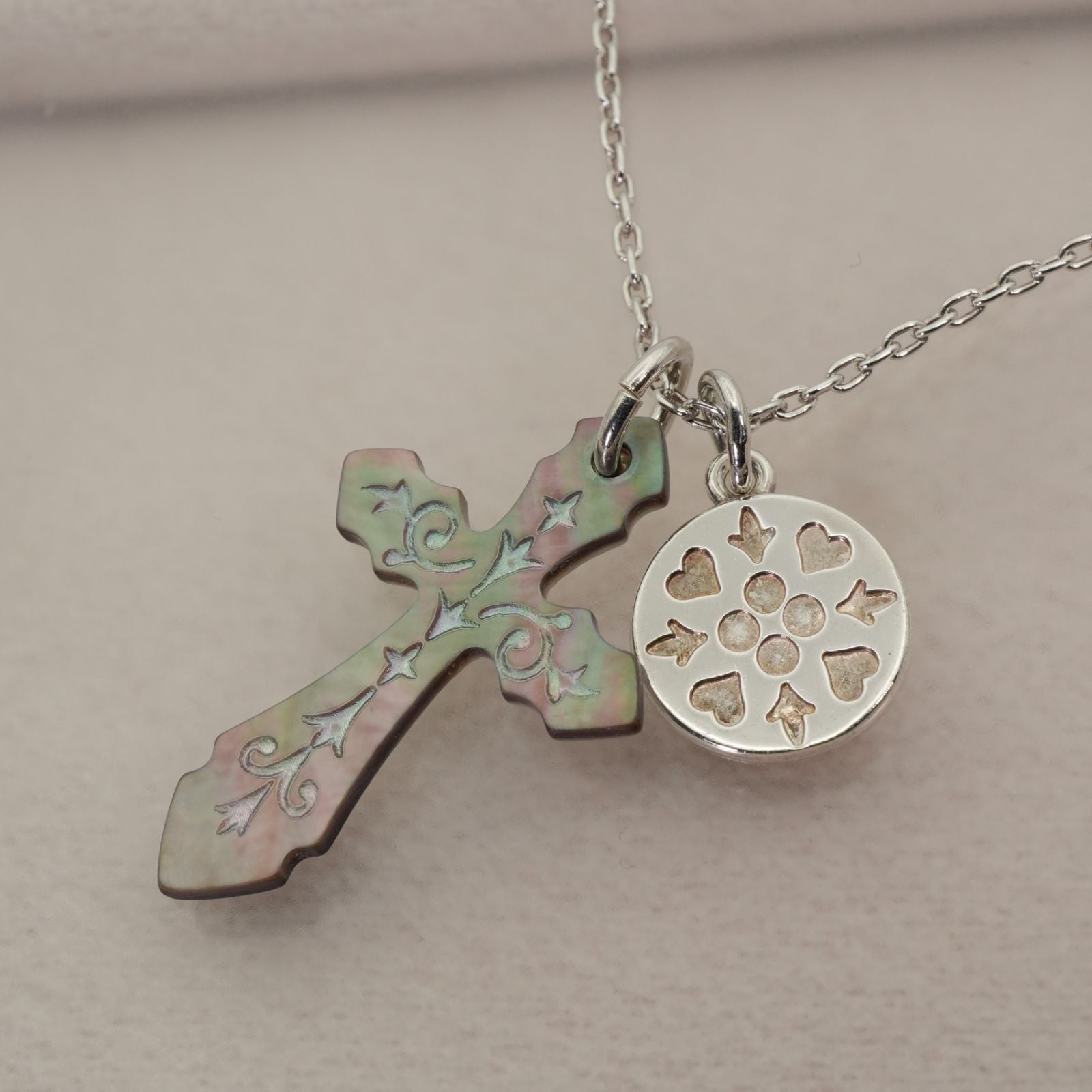 Agete silver necklace with a round shell cross charm on a delicate chain