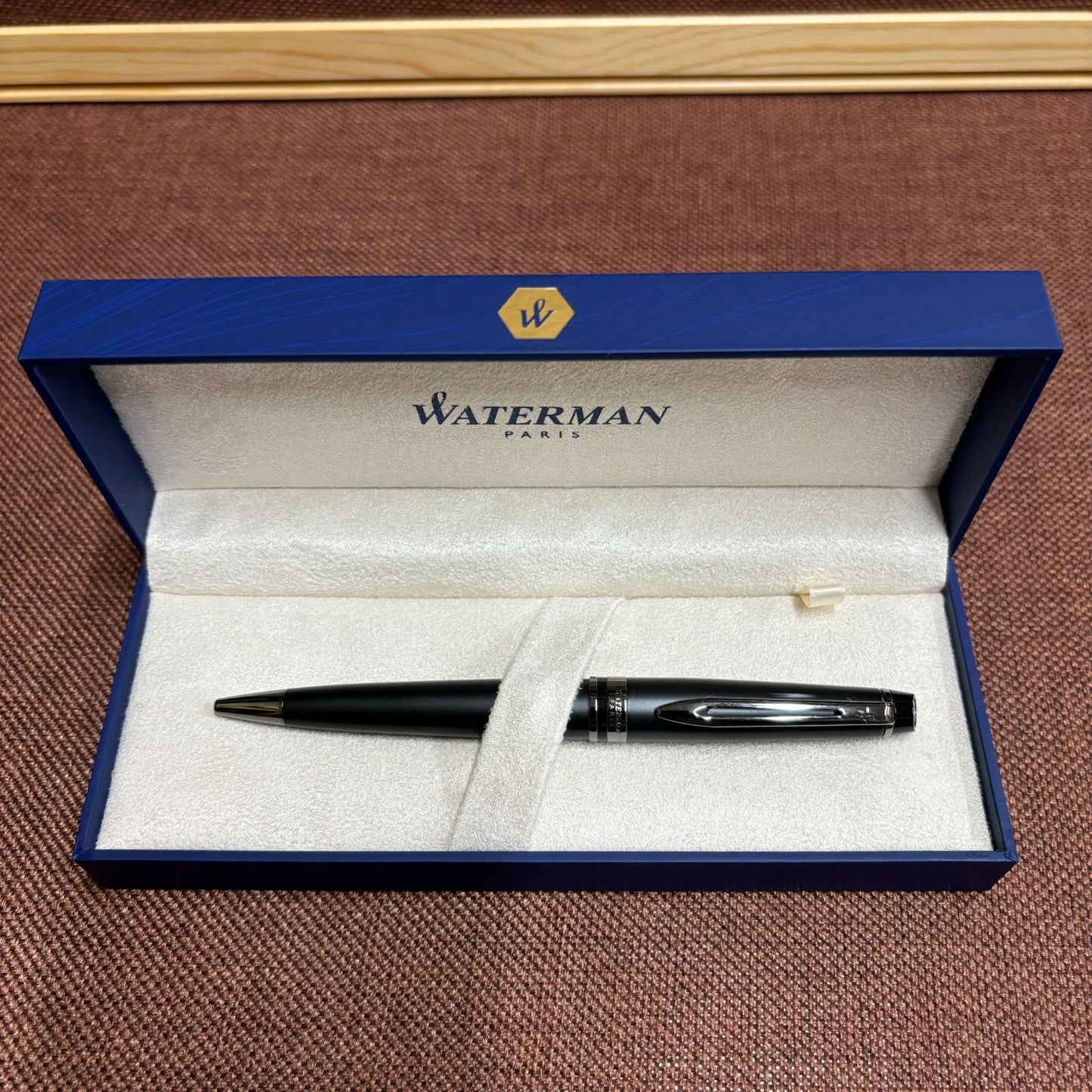WATERMAN Expert Metallic Black ballpoint pen with brass body and twist mechanism shown from side angle