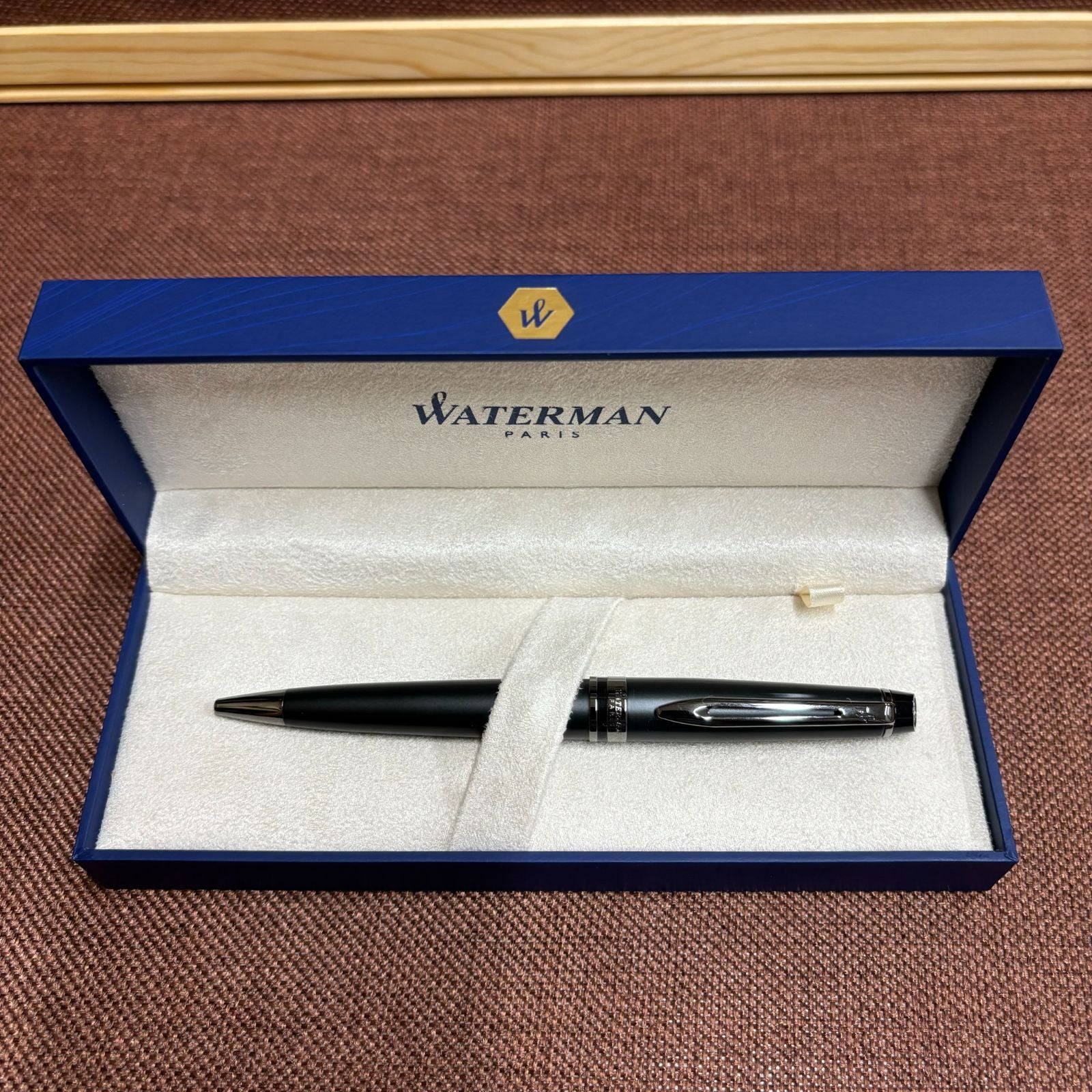 WATERMAN Expert Metallic Black ballpoint pen with brass body and twist mechanism shown from side angle