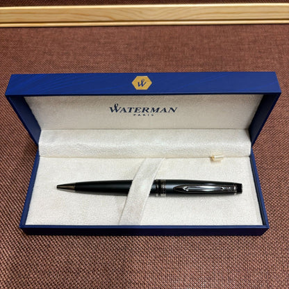 WATERMAN Expert Metallic Black ballpoint pen with brass body and twist mechanism shown from side angle