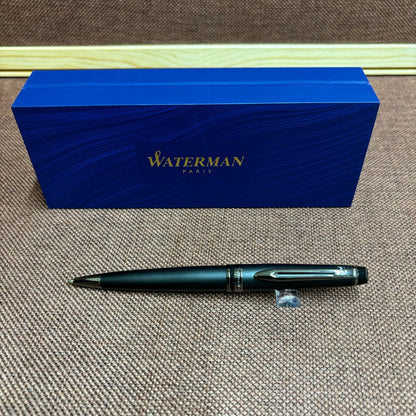 WATERMAN Expert Metallic Black ballpoint pen with brass body and twist mechanism shown from side angle