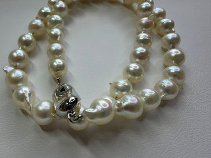 Akoya pearl necklace with 7.5mm white pearls and silver clasp laid flat on white background