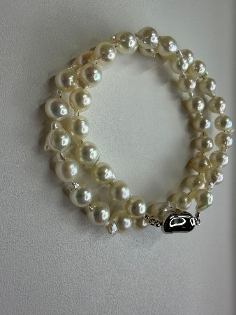 Akoya pearl necklace with 7.5mm white pearls and silver clasp laid flat on white background