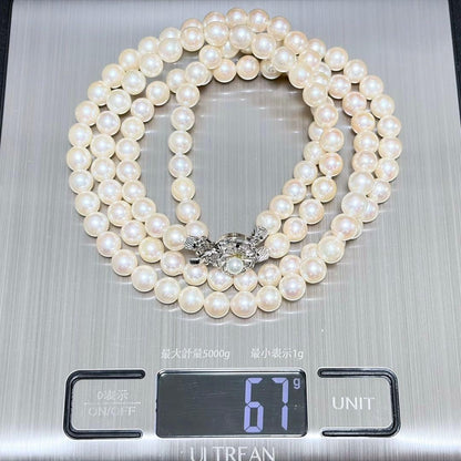 Akoya pearl double strand necklace and matching bracelet with silver clasp laid out on white background