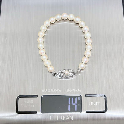 Akoya pearl double strand necklace and matching bracelet with silver clasp laid out on white background