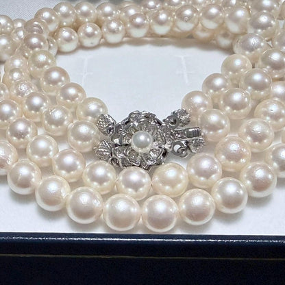 Akoya pearl double strand necklace and matching bracelet with silver clasp laid out on white background