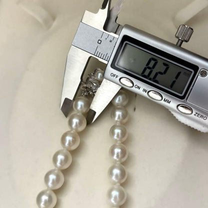 Large white Akoya pearl necklace and matching earrings with 8.5mm pearls and silver accents on white background
