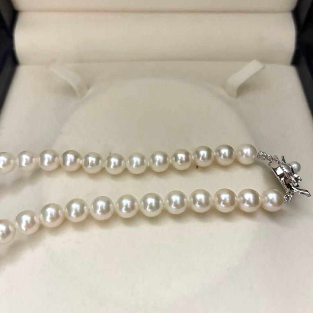 Large white Akoya pearl necklace and matching earrings with 8.5mm pearls and silver accents on white background