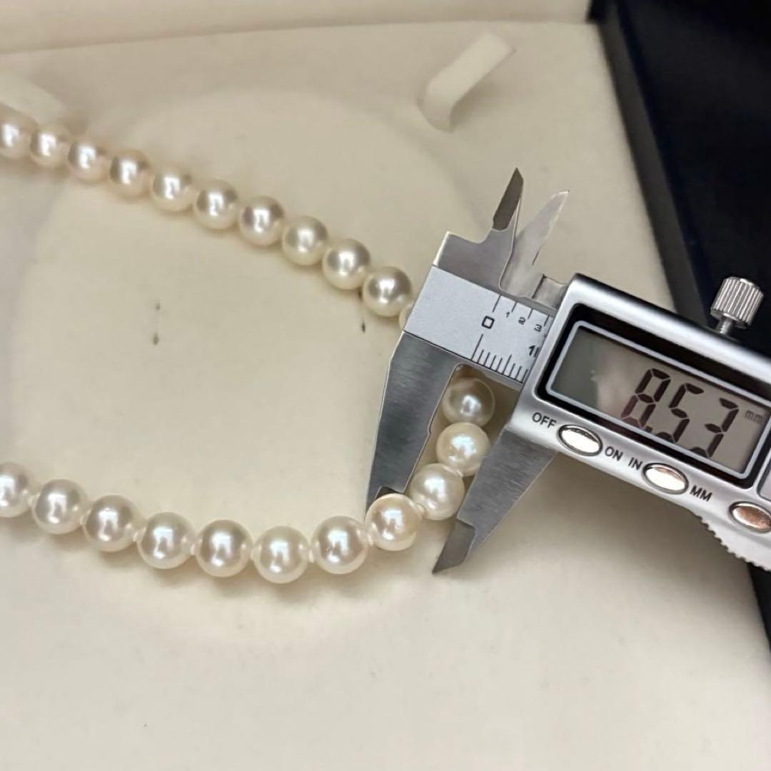 Large white Akoya pearl necklace and matching earrings with 8.5mm pearls and silver accents on white background