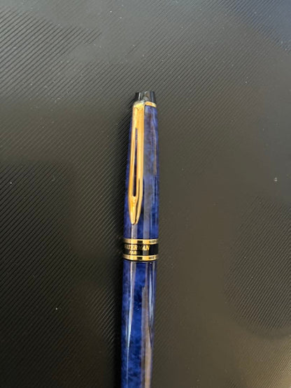 Waterman fountain pen with blue marble finish, gold trim, and medium gold nib on white background