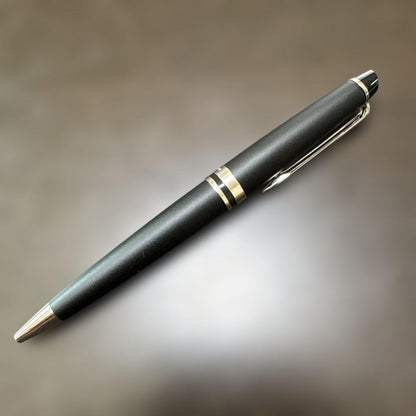 Used Waterman black ballpoint pen with a leather case showing a dent