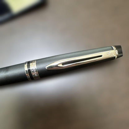Used Waterman black ballpoint pen with a leather case showing a dent