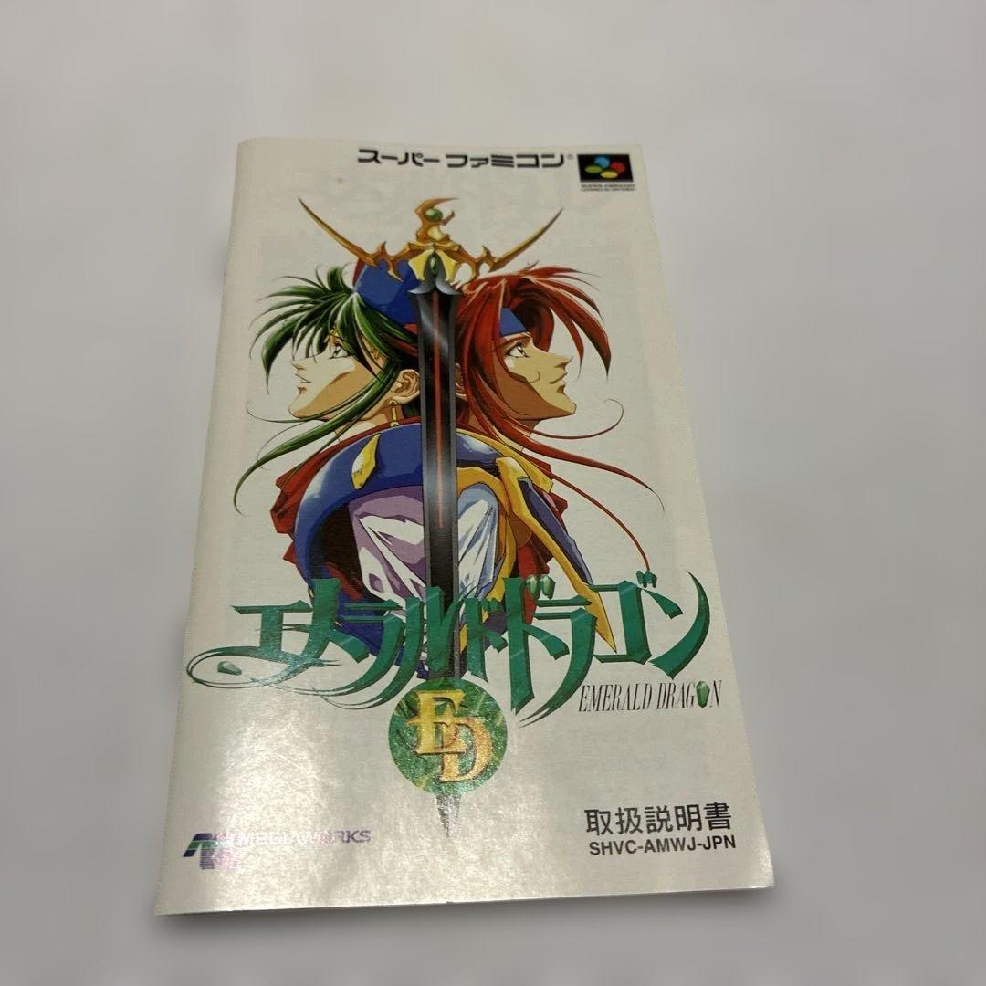 Emeraudo Doragon SNES game with original box, manual, postcard, and pamphlet displayed