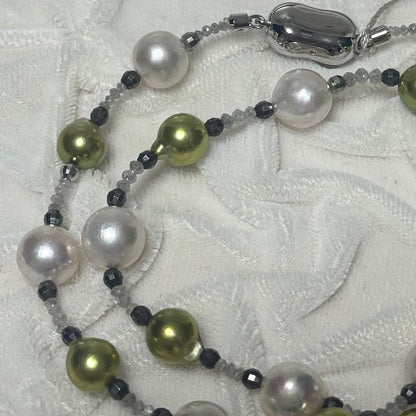 Akoya pearl necklace with pistachio dye pearls and silver findings on a white background